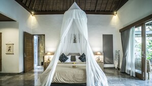 A bedroom with a canopy bed, a large window, and a view of the outdoors. - Villa Kirani Ubud (Ubud)