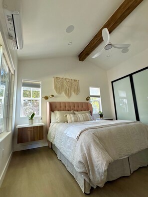 Quarto com cama grande, ventoinha no teto e um enfeite de macramé na parede.
