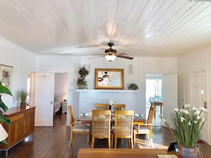 A dining area with a white brick fireplace, wooden dining table, and chairs. - Oceanview Gulf-Front 2BR/2BA | Pass-a-Grille Beach (Saint Pete Beach)