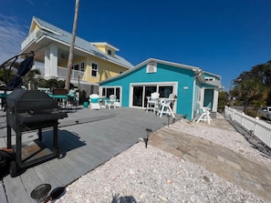A residential property with a deck, outdoor seating, and a garage. - Oceanview Gulf-Front 2BR/2BA | Pass-a-Grille Beach (Saint Pete Beach)