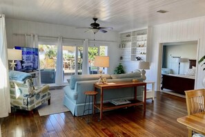A living room with a sofa, a coffee table, a TV, and a ceiling fan.