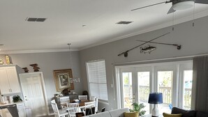 A living room with a grey sofa, a coffee table, and a patterned rug. There is a dining area with a white table and chairs. - Sea Shell Haven 
Family Home, 300 yards from the beach, 2 private docks, Grill! (Placida)