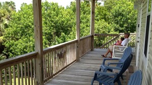 A wooden deck with blue plastic chairs and a railing. - Sea Shell Haven 
Family Home, 300 yards from the beach, 2 private docks, Grill! (Placida)