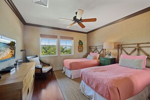 Une chambre d’hôtel avec deux lits, un bureau, une chaise, un ventilateur de plafond et une fenêtre donnant sur un paysage verdoyant.