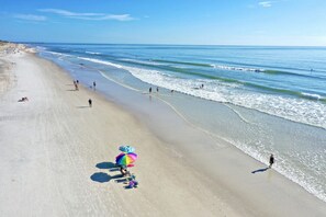 A beach with a clear sky, a pier in the distance, and people engaging in various activities. - Ocean Mist - Beauty and The Beach! - Pool Access (St. Augustine Beach)
