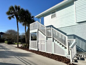 A two-story house with a white exterior, a front porch, and a staircase leading to the second floor.