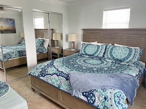 A bedroom with a large bed, a mirror, bedside tables, and a window.