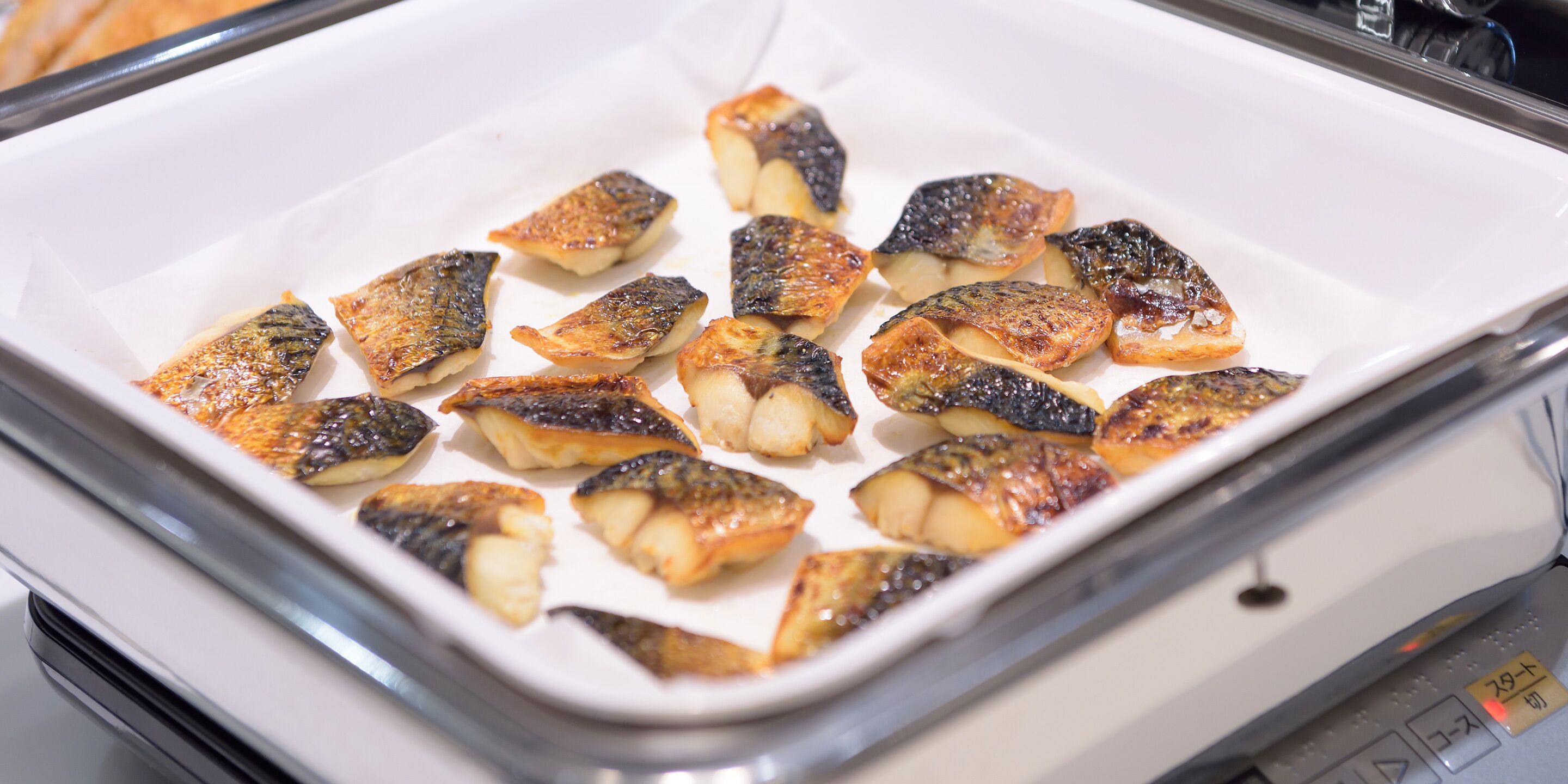 Un vassoio con porzioni di pesce cotto in una pirofila bianca.