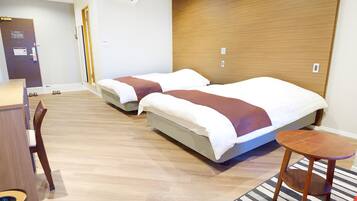 Une chambre d’hôtel avec deux lits, un bureau et une chaise.