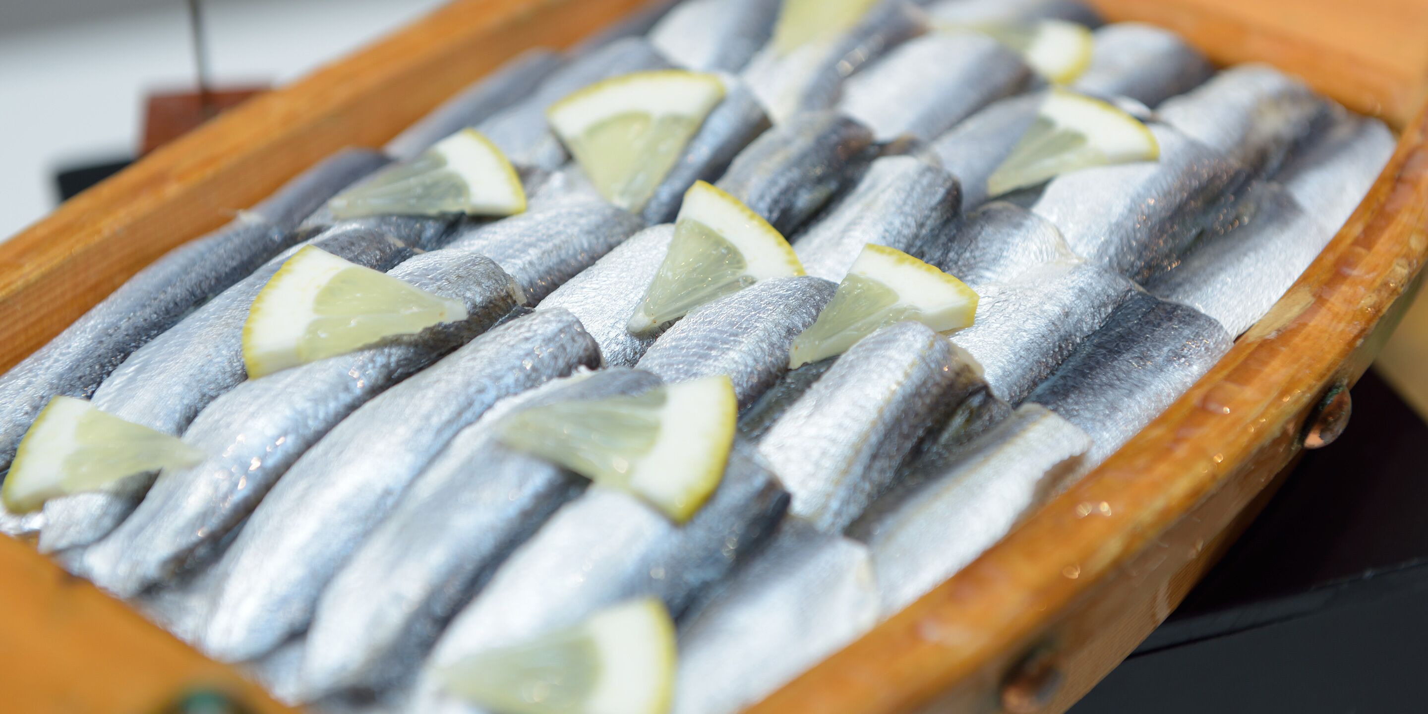 A wooden tray filled with fish and lemon slices.