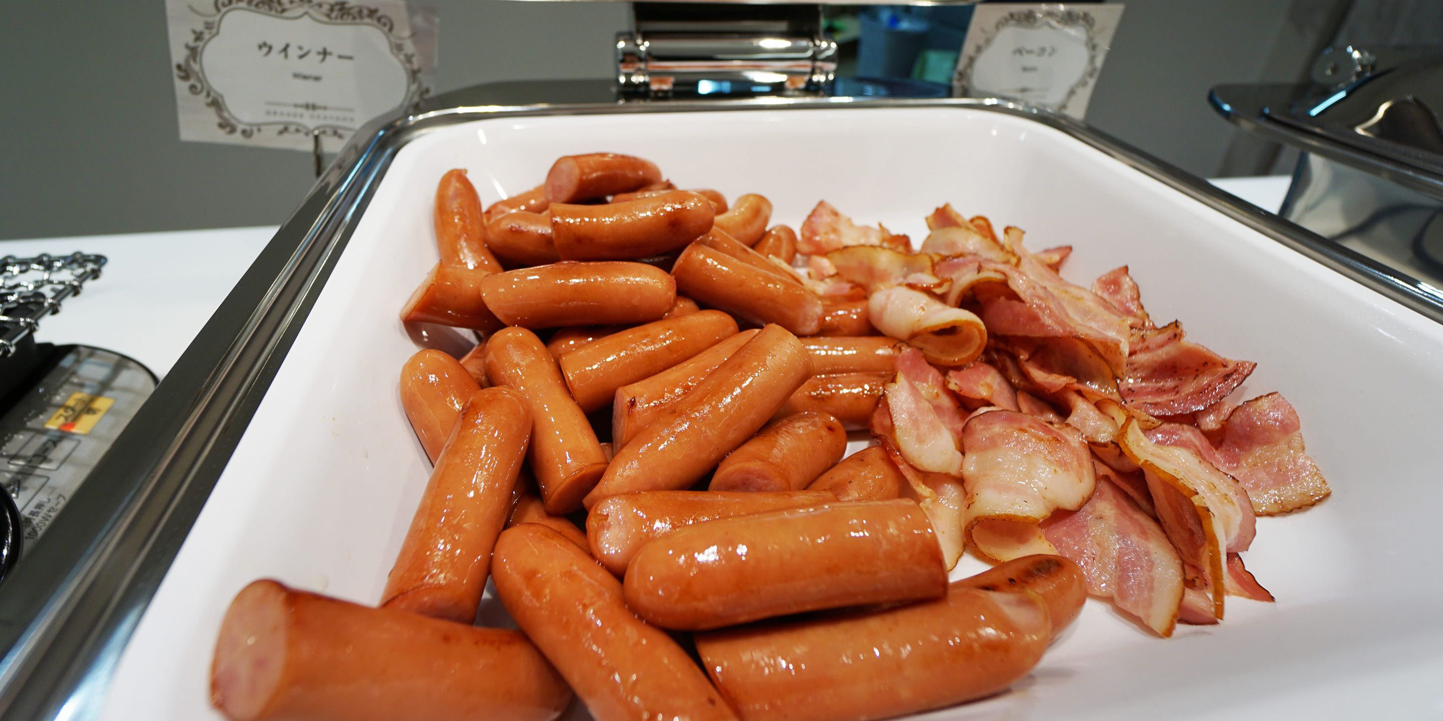A buffet table with sausages and bacon.
