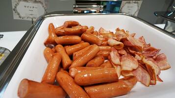 A buffet table with sausages and bacon.