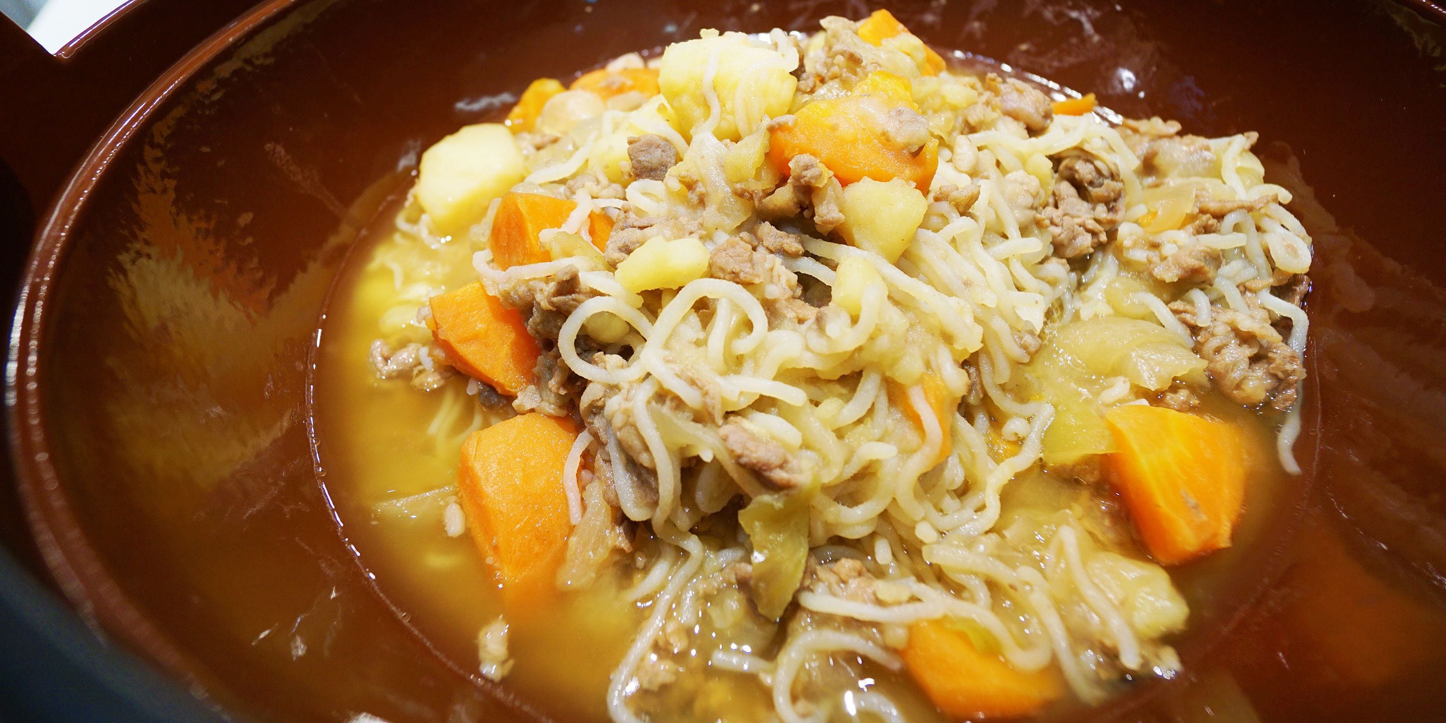 A bowl of soup with noodles, meat, and vegetables.