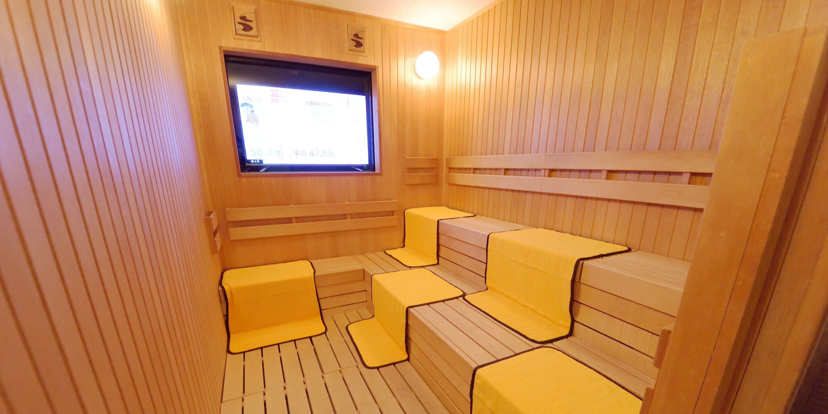 A sauna room with wooden benches and a television screen.