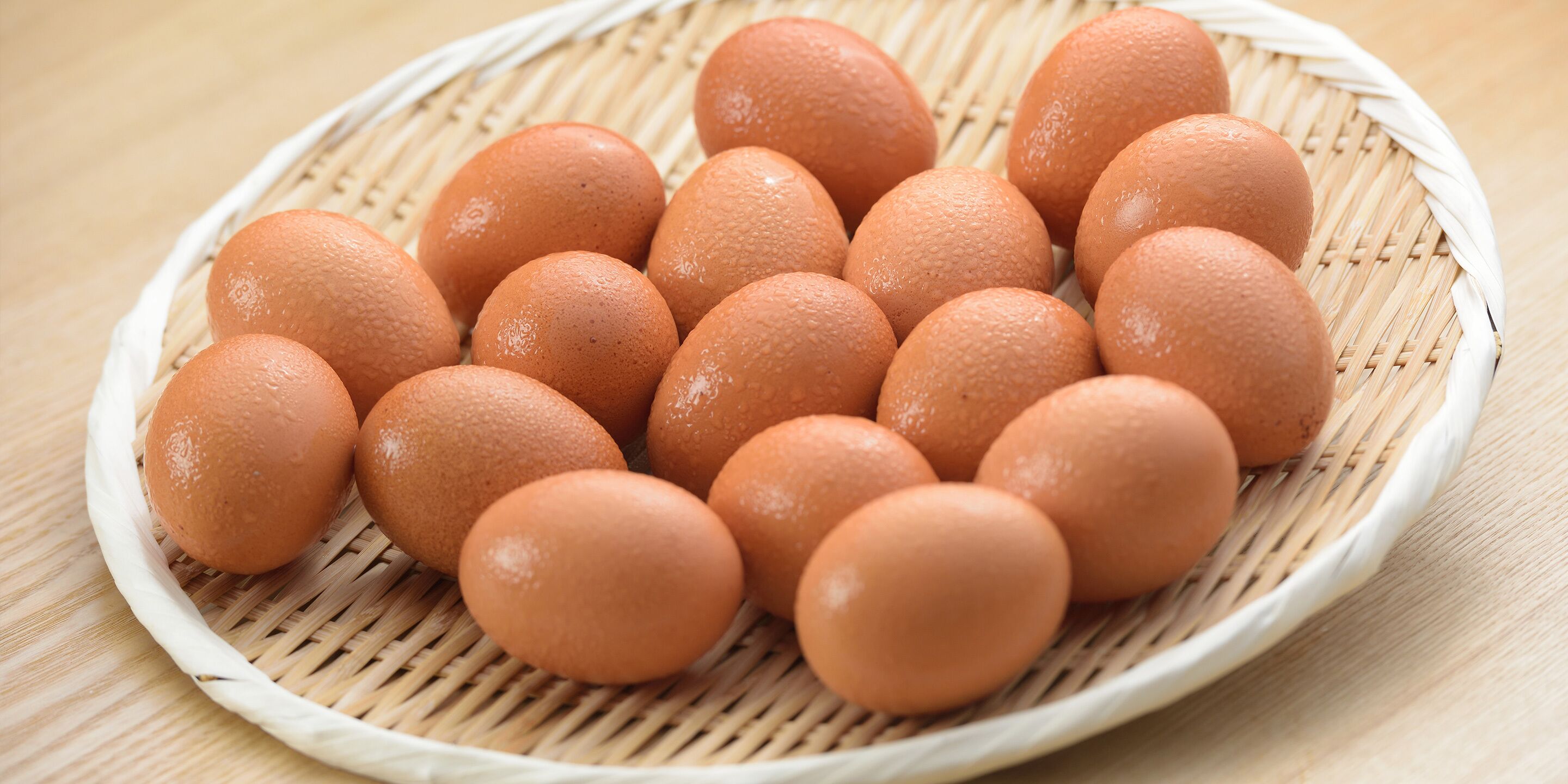 A basket of eggs on a woven mat.