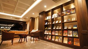A hotel lobby with a large bookshelf filled with books, a leather sofa, and a piano. - Hotel Abest Grande Okayama (Okayama)