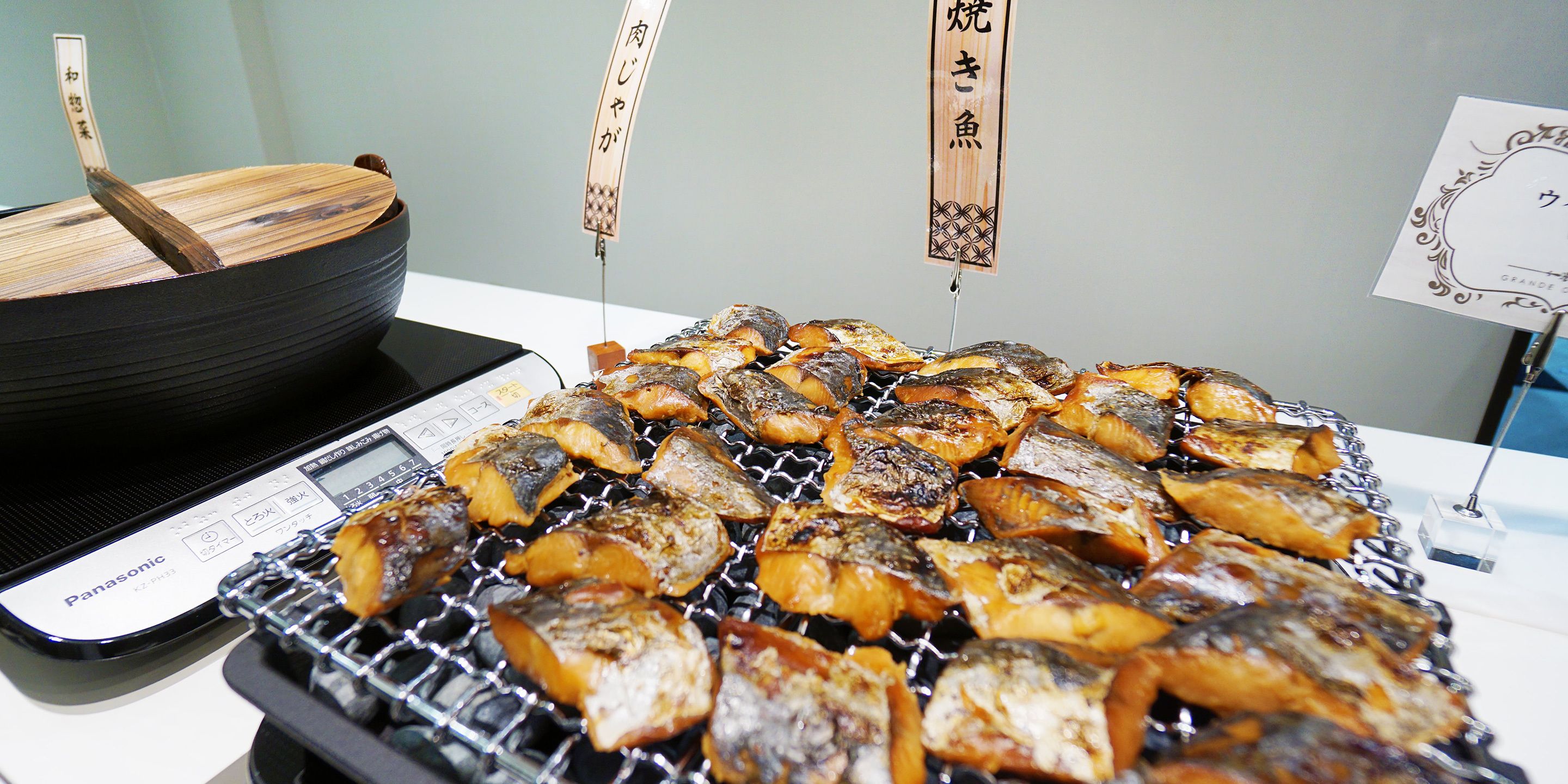 Una parrilla con varios pescados y un cuenco de madera.