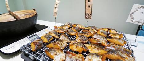 Una parrilla con varios pescados y un cuenco de madera.