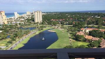 A view of a golf course with a lake, surrounded by residential buildings and a body of water.