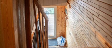 A wooden interior with a staircase leading to a door. A basket with items is placed near the door.