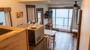 A modern kitchen with a microwave, wooden cabinets, and a dining area with a table and chairs. - Cottage - Lakeside w/private Hottub near Big White (Naramata)