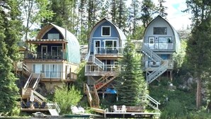 Three cabins with external staircases, wooden decks, and a dock. - Cottage - Lakeside w/private Hottub near Big White (Naramata)