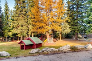 Escape to a serene park setting surrounded by lush trees and a charming playhouse.