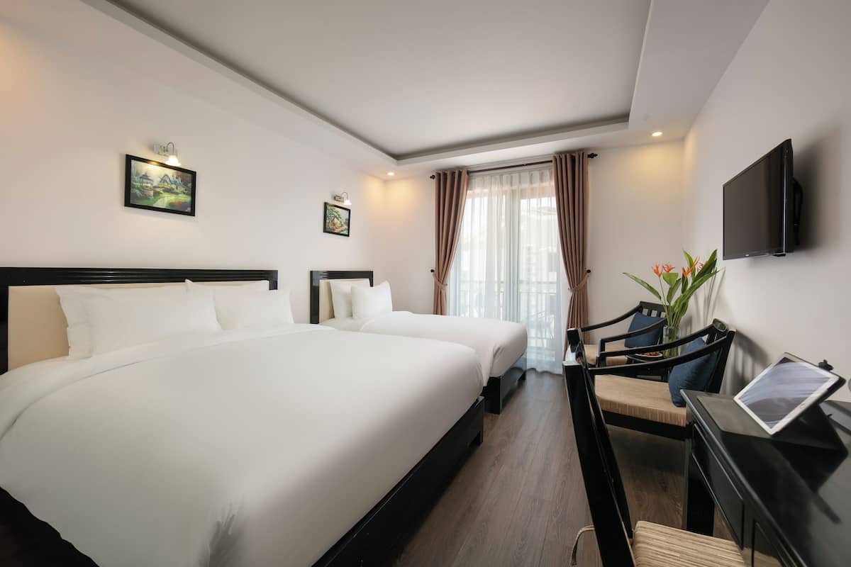 A hotel room with a large bed, a desk with a chair, a flat-screen TV, and artwork on the walls.