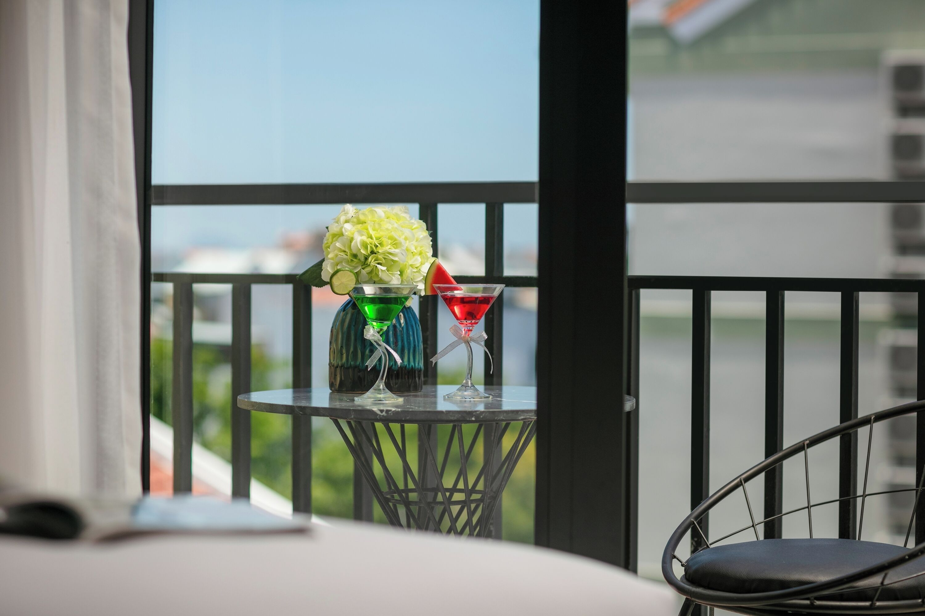 A balcony with a table holding two glasses and a vase of flowers.