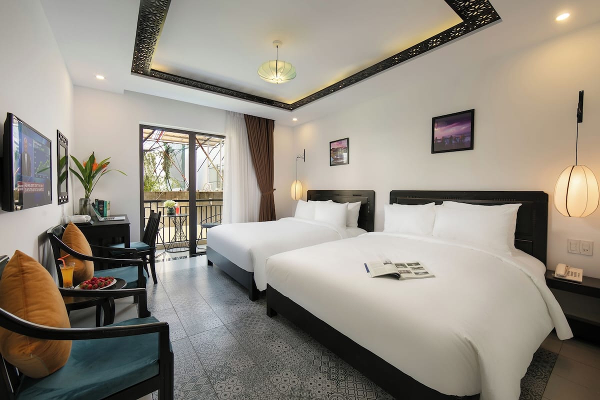 A hotel room with two beds, a desk, a chair, a dining table, and a balcony with a view.