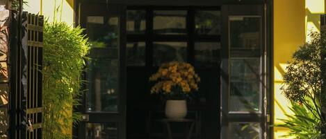 A spa entrance with a green sign, a gated entrance, and potted plants.