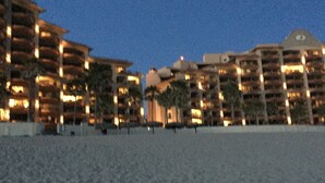 A beachfront hotel with multiple balconies and a pool area.