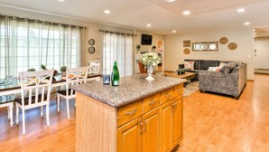 A spacious living area with a kitchen island, wooden cabinets, and a grey sofa.