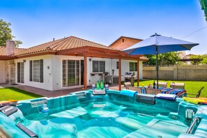 Un patio trasero con piscina, terraza techada y zona de barbacoa.