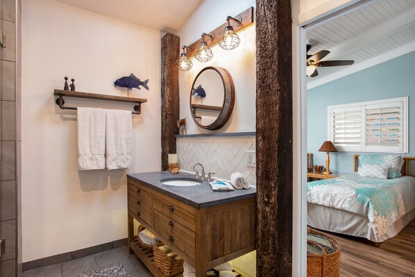 A bathroom with a wooden vanity, a large mirror, and a ceiling fan.