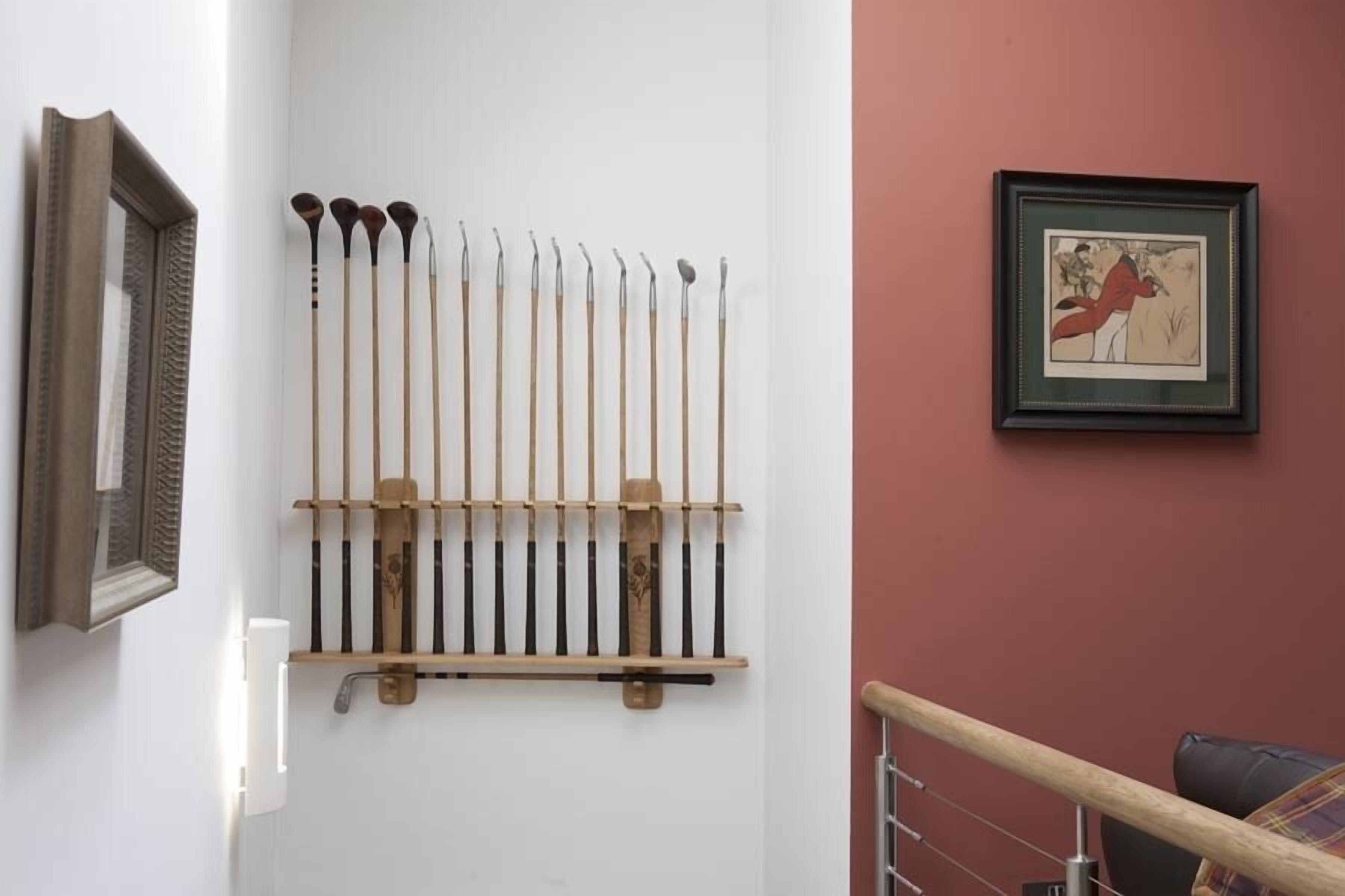 A wall-mounted rack with various tools, a framed picture, and a mirror.