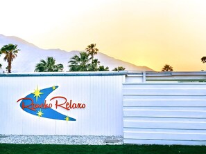 Un edificio con un letrero que dice "Rancho Relaxo" y palmeras al fondo.