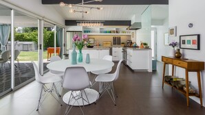 Una cocina moderna con armarios blancos, una isla central y una zona de comedor con una mesa redonda y sillas.