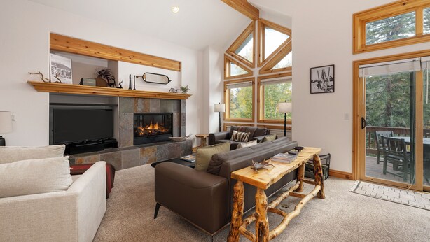 A spacious living room with a fireplace, comfortable seating, and large windows offering a view of the outdoors. - Timber Lake 341 Private outdoor hot tub, views, garage parking (Winter Park)
