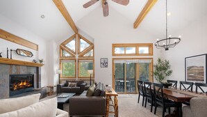 A spacious living room with a fireplace, a dining area, and large windows. - Timber Lake 341 Private outdoor hot tub, views, garage parking (Winter Park)