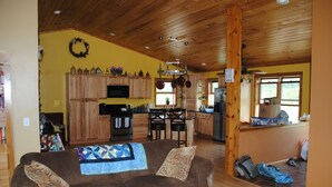 A spacious living room with a brown sofa, a quilt, and a wooden ceiling. - Longview Cottage with views to compliment its name and close to cooperstown (Mount Vision)