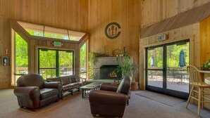 Ein Holzinnenraum mit Ledersofas, einem Kamin und Blick ins Freie.
