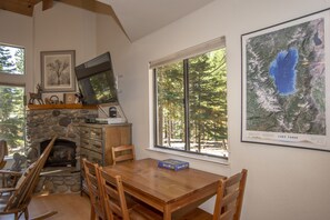 A dining area with a stone fireplace, wooden table, and chairs.