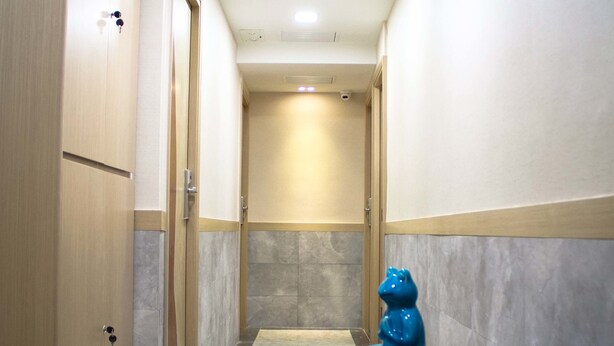 A narrow hallway with a red chair, a blue sculpture, and a small table. - Ace Apartments Hong Kong (Kowloon)