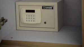 A Safewell safe in a room with a wooden floor and a white wall. - Ace Apartments Hong Kong (Kowloon)