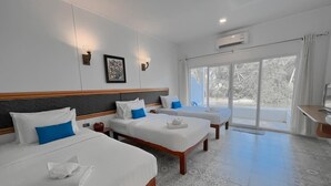 Habitación de hotel con tres camas, un ventanal grande y un equipo de aire acondicionado.