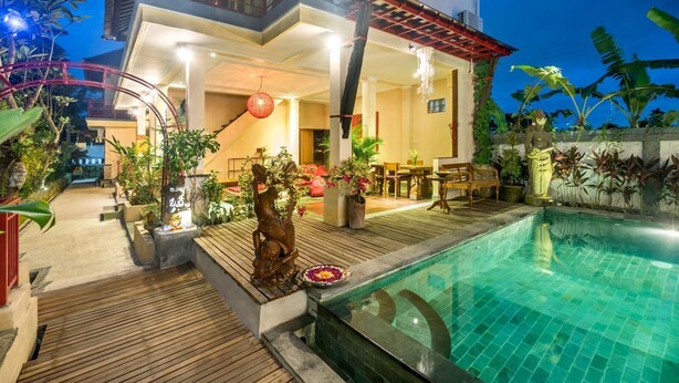 Zona junto a la piscina con terraza de madera, una estatua y un comedor.
