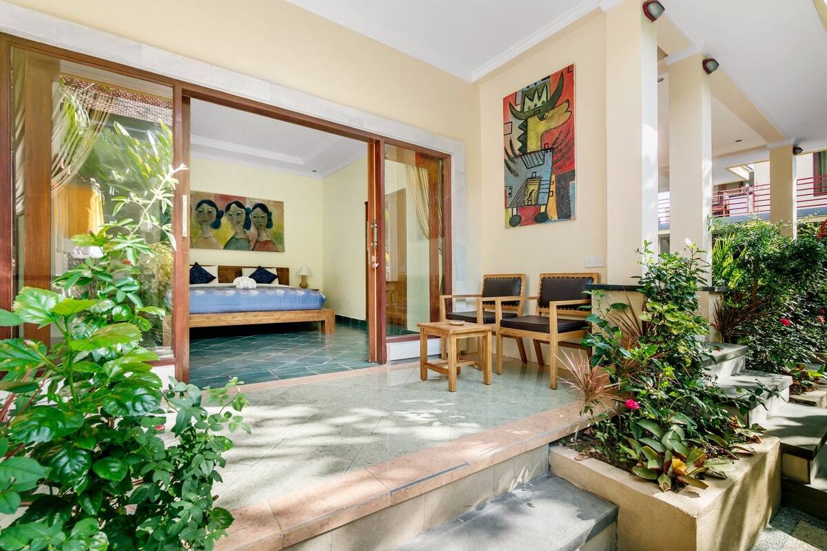 A spacious patio area with a dining table and chairs, a sofa, and a large sliding glass door leading to a bedroom.
