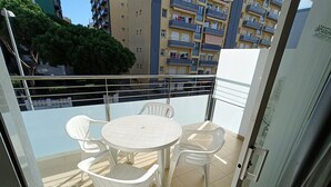 A balcony with a round table and four chairs, overlooking a cityscape with tall buildings. - APCOSTAS Lotus / One Bedroom (Blanes)