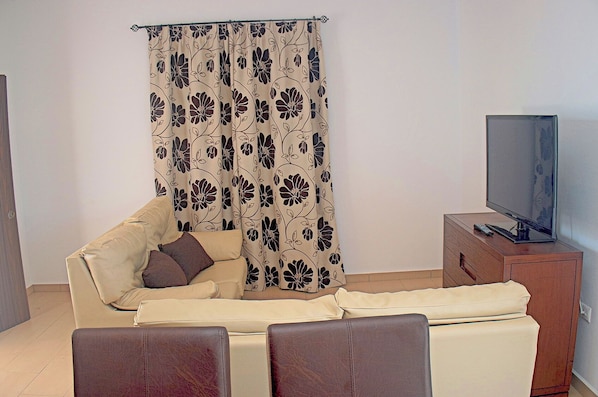 A living room with a sofa, a TV on a wooden stand, and a floral curtain. - Villa with private pool, town outskirts (CONIL DE LA FRONTERA)